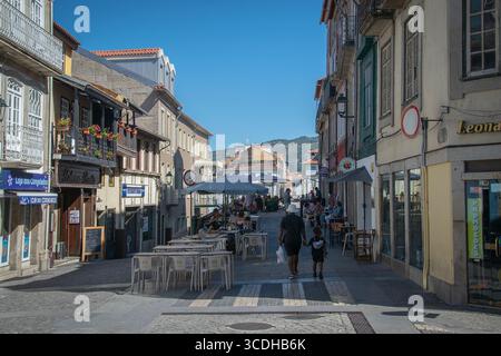 Chaves, Portugal: 13. August 2023: Ein breites Bild einer lebhaften Straße mit Einheimischen und Touristen, die an einem sonnigen Tag shoppen und spazieren gehen, Chave Stockfoto