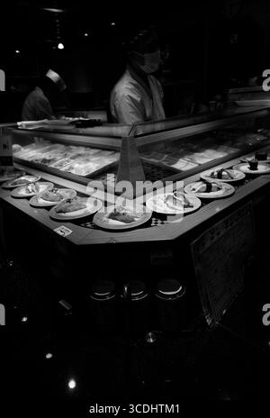Der Sushi-Koch bereitet frische Teller in einem Sushi-Restaurant mit Förderband in Asakusa, s&W Tokio, zu Stockfoto