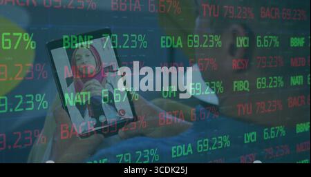 Smartphone zeigt Live-Anruf am Schreibtisch mit Frau in rosa Hijab und Laptop, Stockticker-Overlay Stockfoto