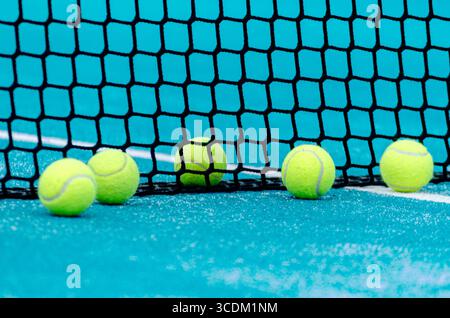 Eine Linie gelber Padelbällchen, die auf dem Netz auf einem türkisfarbenen Trainingskonzept liegen Stockfoto