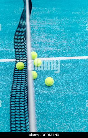 Ein Hochwinkelblick auf gelbe Padelbällchen, die im Netz verstreut sind, bei einem türkisfarbenen Trainingskonzept Stockfoto