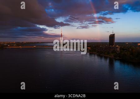Sonnenuntergang über Riga mit dem Rigaer Fernsehturm und dem schwachen Regenbogen im Himmel Stockfoto