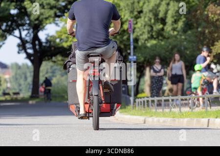 Mann in Shorts fährt Lastenrad Stockfoto