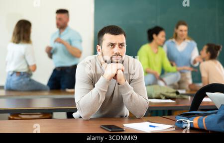 Frustrierter Mann Student sitzt getrennt im Klassenzimmer in der Pause zwischen den Lektionen Stockfoto
