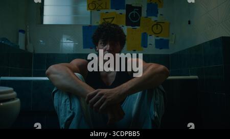 Einsamer Mann, Der Auf Dem Boden Des Badezimmers Sitzt Stockfoto