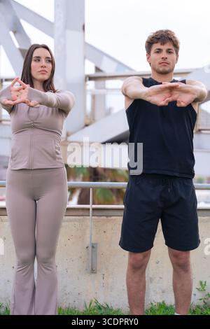 Junge Paare, die die Arme im Freien Strecken, bevor sie in der Stadt trainieren Stockfoto