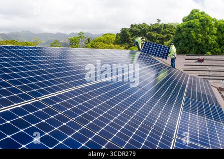 Männer mit Sicherheitsgurten, die auf dem Dach stehen und das LG NeonR installieren DC-Photovoltaikpaneele auf Aluminiumschienen bei einer Wohnphotovoltaik Installieren Stockfoto