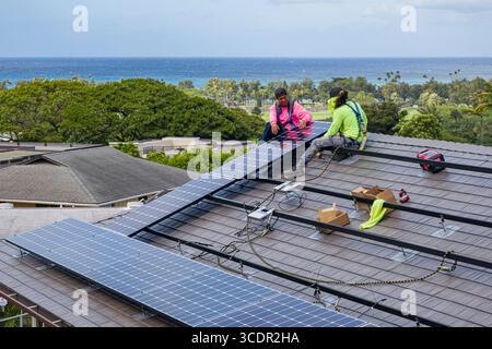 Männer tragen Sicherheitsgurte stehen auf dem Dach Befestigung LG NeonR DC-Photovoltaikpaneele auf Aluminiumschienen bei einer Wohnphotovoltaik Installation Stockfoto