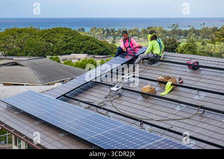 Männer tragen Sicherheitsgurte stehen auf dem Dach Befestigung LG NeonR DC-Photovoltaikpaneele auf Aluminiumschienen bei einer Wohnphotovoltaik Installation Stockfoto