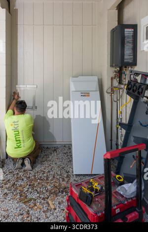 Junger Mann installiert Wandhalterung für Generac PWRcell Batterieschrank während einer privaten Photovoltaik-Installation, Honolulu, Oahu, Hawaii, USA Stockfoto