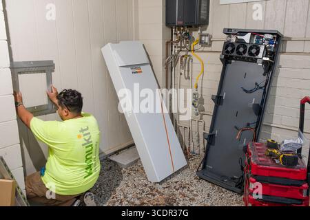 Junger Mann installiert Wandhalterung für Generac PWRcell Batterieschrank während einer privaten Photovoltaik-Installation, Honolulu, Oahu, Hawaii, USA Stockfoto