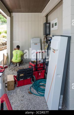 Junger Mann installiert Wandhalterung für Generac PWRcell Batterieschrank während einer privaten Photovoltaik-Installation, Honolulu, Oahu, Hawaii, USA Stockfoto