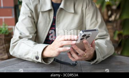 Nahaufnahme einer Frau, die am Telefon nachsieht. Hände halten und auf dem Telefonbildschirm blättern. Stockfoto