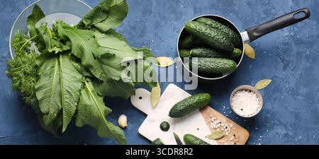 Zusammensetzung mit frischen Gurken und Zutaten zur Konservierung auf blauem Hintergrund Stockfoto