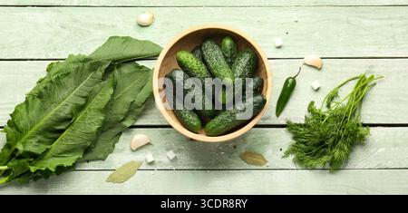 Zusammensetzung mit frischen Gurken und Zutaten zur Konservierung auf grünem Holzhintergrund Stockfoto