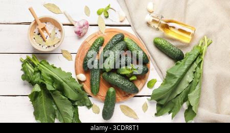 Zusammensetzung mit frischen Gurken und Zutaten zur Konservierung auf weißem Holzhintergrund Stockfoto
