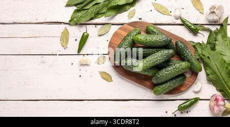 Zusammensetzung mit frischen Gurken und Zutaten zur Konservierung auf weißem Holzhintergrund Stockfoto