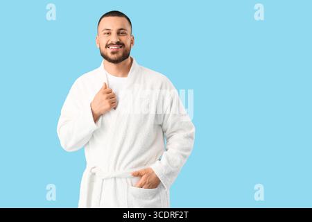 Lächelnder, gutaussehender Mann im Gewand auf blauem Hintergrund Stockfoto