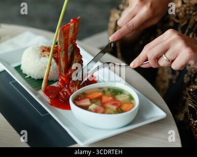 Die Hand, die sich zum Verzehr von Leckereien zubereitete Rippchen aus Roastbeef sind in Honig getränkt. Stockfoto