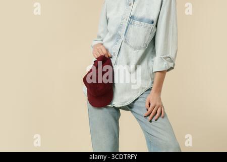 Serie von Studiofotos von Frauen in modernem Freizeitoutfit, blaue Jeans, weißes Tanktop, Jeans-Overshirt, rote Baseballmütze aus Denim Stockfoto