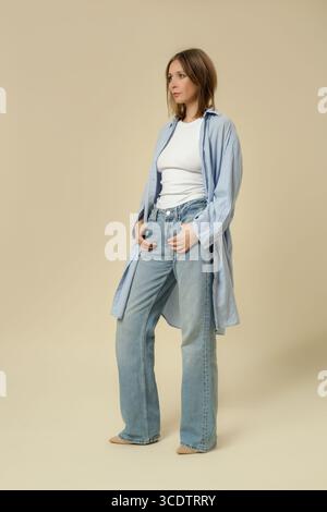 Eine Serie von Studiofotos von Frauen im klassischen Basic-Outfit – blaue Jeans, weißes Tanktop und langes Hemd aus blauer Baumwolle mit Knopfverschluss Stockfoto