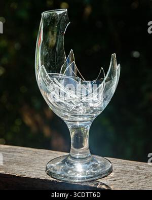 Zerbrochenes Weinglas mit zersplitterten Stücken auf dunkelblauem Hintergrund Stockfoto