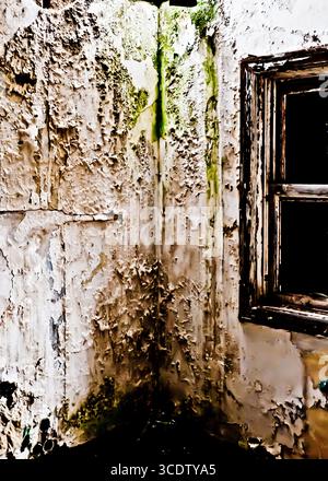 Ein Bild einer Ecke eines Raumes mit abblätternder Farbe und einem Fenster. Stockfoto