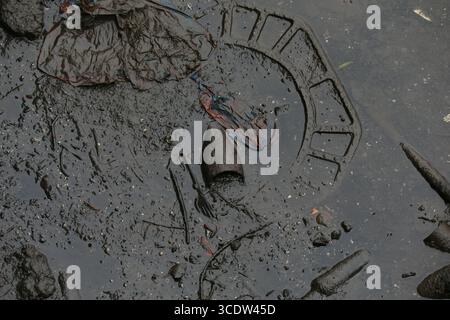 Dublin, Irland - 25. Juli 2025 - weggeworfene Gegenstände, darunter ein Glas und die Basis eines mit Schmutz bedeckten Verkehrkegels, sichtbar am Fluß des Liffey bei Ebbe im Stadtzentrum von Dublin Stockfoto
