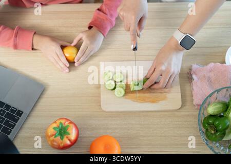 Gesundes Kochen. Die Zubereitung von frischem Gemüse für einen nahrhaften Salat mit kindlicher Beteiligung. Stockfoto