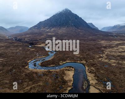 Aus der Vogelperspektive die dramatische Begegnung von Erde und Himmel, wo sich die berühmte Buachaille Etive Mòr majestätisch über dem sich schlängelnden Fluss Coupall erhebt, Glencoe, Schottland, Großbritannien. Stockfoto