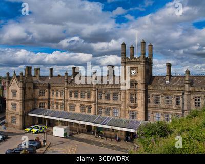 Shrewsbury, Großbritannien - 07. August 2025: Historische Fassade und Uhrenturm des Bahnhofs Shrewsbury, Shropshire, England, unter dynamischen Sommerwolken und hellem Nachmittagslicht. Stockfoto