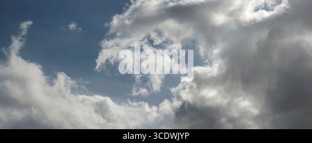 Wirbel aus weißen Wolken gegen einen blauen Himmel Stockfoto