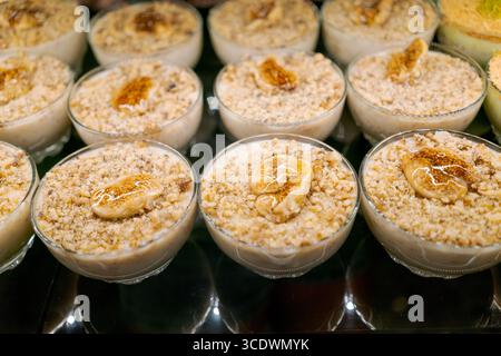 Reihe kleiner Schüsseln gefüllt mit einem Dessert aus Nüssen und Bananen. Die Schalen stehen auf einem Tisch Stockfoto