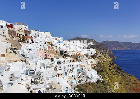 Weiße und bunt bemalte Ferienhäuser, orthodoxe Kirche mit blauer Kuppel am Rand der Caldera, Klippen, Oia, Thira, Santorini, Kykladen, Greec Stockfoto