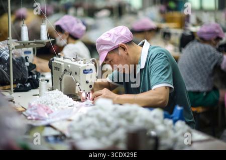 (250814) -- PEKING, 14. August 2025 (Xinhua) -- Arbeiter verarbeiten Stoffe in einer Spielzeugfabrik in Dongguan, südchinesischer Provinz Guangdong, 11. August 2025. In China haben in letzter Zeit immer beliebter werdende Taschen-Charms gewonnen, die es jungen Menschen ermöglichen, sich auszudrücken und gleichzeitig ein aufmunterndes Geschäft anzuheizen. Die Daten des E-Commerce aus dem diesjährigen Einkaufsbummel „18. Juni“ haben gezeigt, dass trendiges Spielzeug zu den stärksten Sektoren im „neuen Konsum“ des Landes zählt. Taschen-Charms haben sich zu einer vollwertigen Industriekette entwickelt, die von Originaldesigns bis hin zu geistigem Eigentum reicht Stockfoto