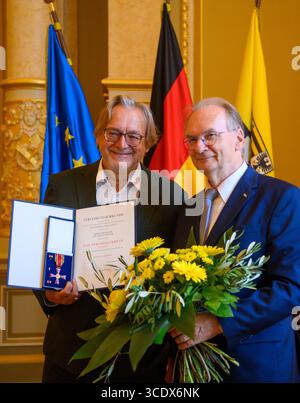 14. August 2025, Sachsen-Anhalt, Magdeburg: Reiner Haseloff (r, CDU), Ministerpräsident von Sachsen-Anhalt, überreicht im Ballsaal des Landeskanzleramtes Harald Meller, Sachsen-Anhalters Landesarchäologe, das Bundesverdienstkreuz. Meller ist Direktor des Landesamtes für Denkmalpflege und Archäologe und des Landesmuseums für Vorgeschichte Halle, amtierender Leiter der Kulturstiftung Dessau-Wörlitz und Kulturbotschafter für Sachsen-Anhalt. Er prägt die Archäologie seit Jahrzehnten und rettete einst die Nebra Sky Disk aus den Händen der Plünderer. Foto Stockfoto