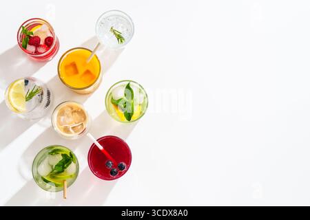 Eisgetränke auf weißem Hintergrund. Limonade, Mojito, Himbeer-Limonade, Tonic Water mit frischem Obst. Draufsicht mit Platz für Text. Stockfoto