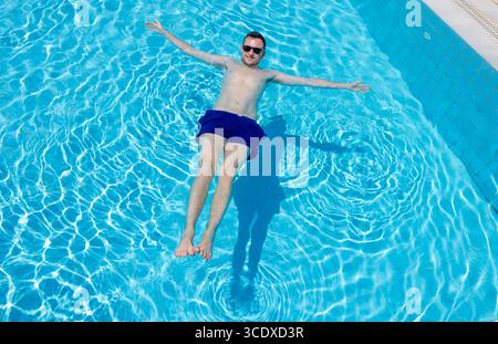 Ein junger Mann in seinen Sommerferien entspannt sich in einem Schwimmbad in Griechenland. Stockfoto