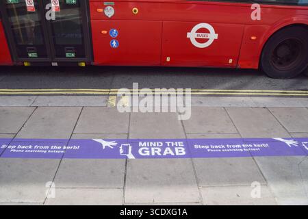 London, Großbritannien. August 2025. Ein Bus fährt an einem Schild mit der Aufschrift „Mind the Grab“ auf dem Bürgersteig in der Oxford Street vorbei, das einen „Hotspot“ für Telefonschnappen markiert und die Leute dazu drängt, nicht in der Nähe des Bordsteines zu laufen, um zu vermeiden, dass ihre Telefone gestohlen werden. Telefondiebstähle auf den Straßen Londons haben in den letzten Jahren zugenommen. Quelle: Vuk Valcic/Alamy Live News Stockfoto
