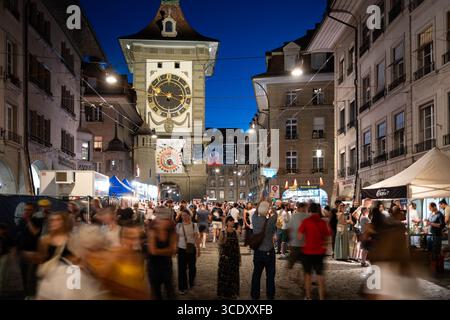 07-08-2025 Bern, Schweiz. Menschenmassen genießen das Street Food und die Aufführungen des Straßenmusikfestivals Buskers am Abend. Blaue Stundenanzeige, l Stockfoto