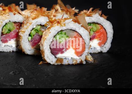Köstliche Uamaki-Sushi-Brötchen mit Thunfisch, Lachs, Gurke und Frischkäse auf schwarzem Hintergrund Stockfoto