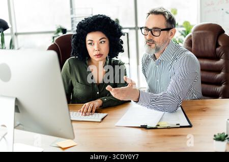 Professionelle Kollegen arbeiten in einem modernen Bürobereich zusammen und diskutieren Ideen, Teamdynamik und Unternehmensstrategien Stockfoto