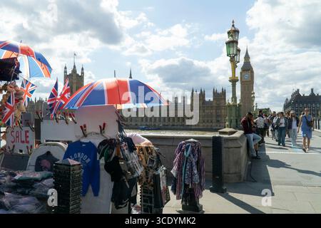 Großbritannien Wetter, 14. August 2025: Als die Temperaturen im Zentrum Londons wieder 27 Grad erreichten, verkauft ein Souvenirstand an der Westminster Bridge union Jack Flags, Regenschirme und Teddybären, mit dem Elizabeth Tower of the Houses of Parliament (der Big Ben beherbergt). Quelle: Anna Watson/Alamy Live News Stockfoto
