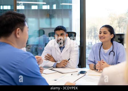 Ärzte und Krankenschwestern führen während eines Meetings an ihrem Arbeitsplatz ein fokussiertes Gespräch. Die professionelle Atmosphäre unterstreicht Teamarbeit und Kommunikation unter medizinischen Fachleuten Stockfoto