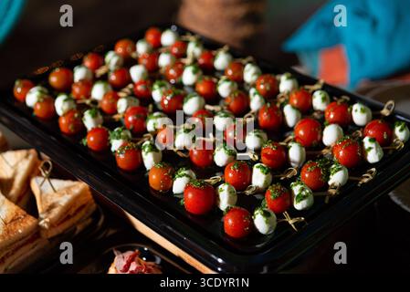 Ein lebhaftes Arrangement aus Caprese-Spießen mit saftigen Tomaten, Mini-Mozzarella-Bällchen und frischem Pesto. Diese Vorspeisen sind ideal für Partys und geben Col Stockfoto