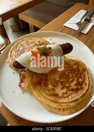 Pfannkuchen mit Würstchen und sonnigen Eiern zum Frühstück im Restaurant Stockfoto