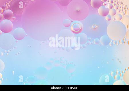 Weiche rosa, blaue und lilafarbene Öltropfen in Wasser-Makrotextur. Sanfter Pastellverlauf mit runden Formen für kreative Hintergründe und elegante Designs Stockfoto