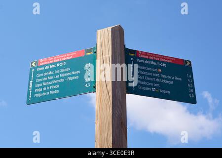 Viladecans. Barcelona - 14. August 2025: Nahaufnahme eines Wegweisers mit Wegbeschreibungen zu lokalen Stränden und Wegen. Die Schilder zeigen auch Entfernungen in KI an Stockfoto