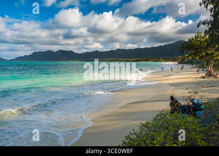 Frau, die Angelrute und Ausrüstung am Strand an der Bellows Air Force Station, Waimanalo, Honolulu, Oahu, Hawaii, USA anpasst Stockfoto