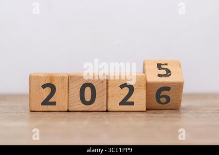 Wende des neuen Jahres. Holzblöcke mit 2025 wechseln zu 2026, die Zahl fünf ist bereits verblasst. Stockfoto